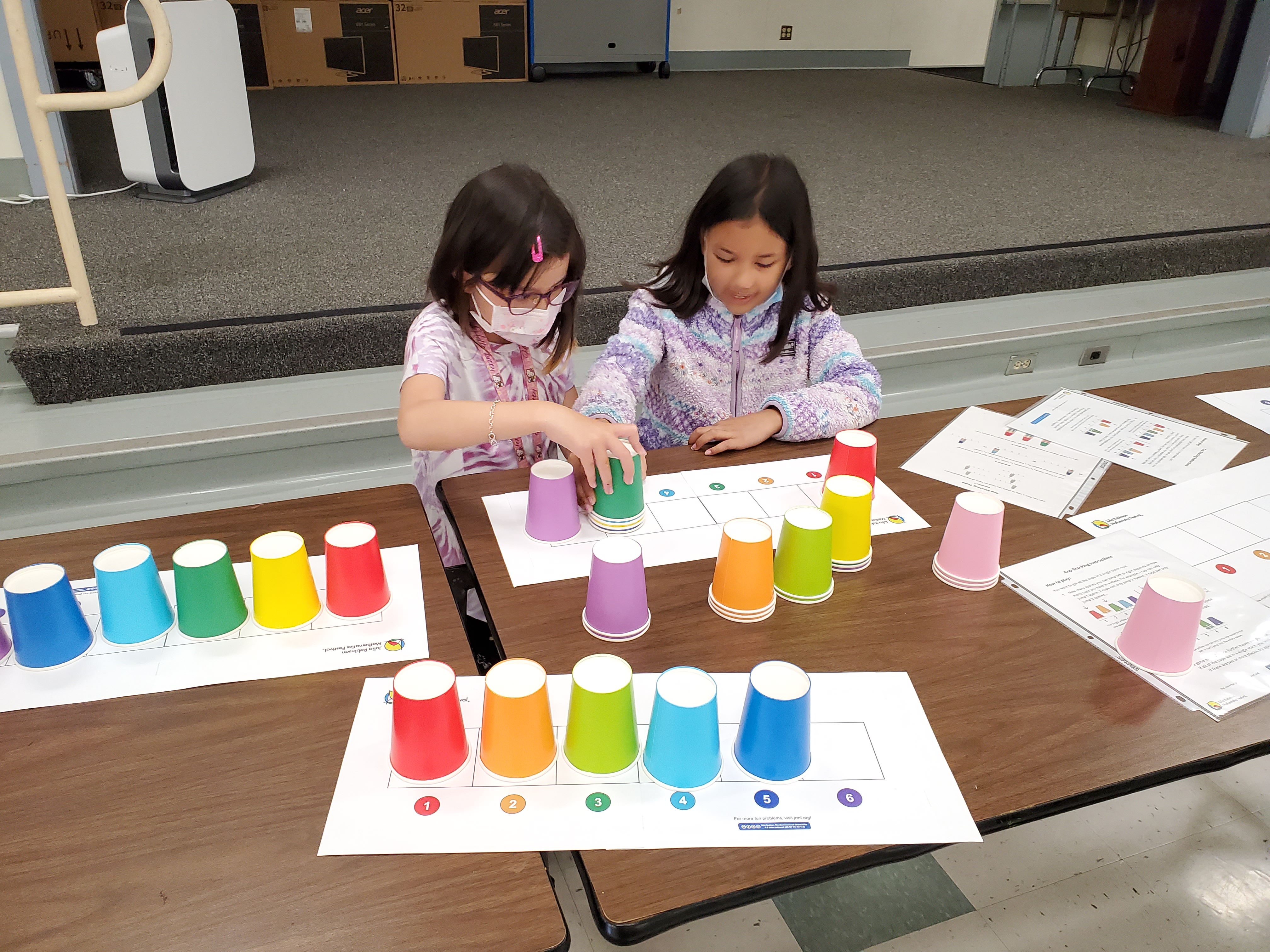 two girls play cup stacking