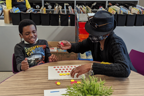 Boy laughs while playing with yellow and red tokens with adult